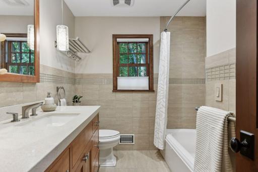 Well-appointed main level full bath with stylish tile flooring, a shower/tub combo, and ample built-in storage