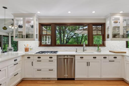 The kitchen features a gas cooktop and sink overlooking oversized windows with panoramic views of the backyard and Purgatory Park
