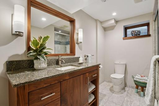 Stylish lower-level bathroom featuring a tiled shower/tub, modern vanity, and a bright window accent