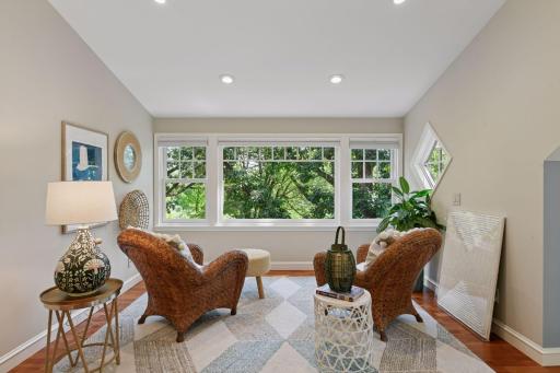 Cozy sitting area in the primary bedroom with large window overlooking lush treetops - perfect for relaxing with natural light and serene views