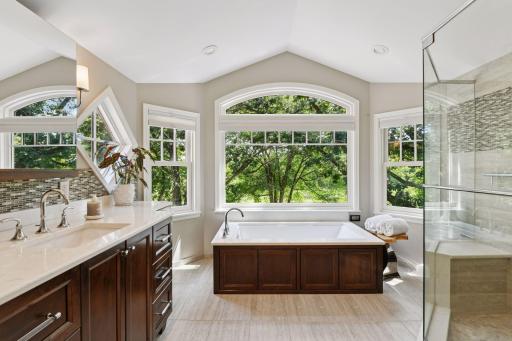 This spa-inspired primary bath offers a serene retreat with a deep soaking tub framed by picture windows