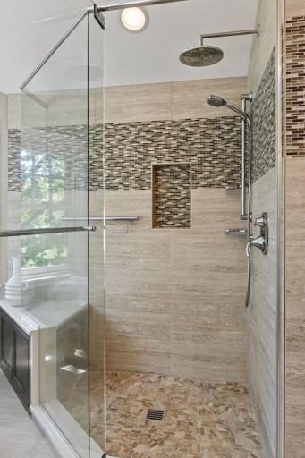 Luxurious glass-enclosed walk-in shower with stone tile flooring, full tile surround, and a sleek rain shower for a spa-like experience