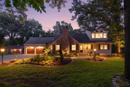 Striking twilight curb appeal with glowing landscape lights and lush, manicured gardens