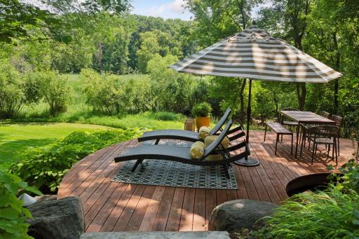 Graceful circular deck with space for lounging and dining, offering serene backyard views and a scenic overlook of Purgatory Park
