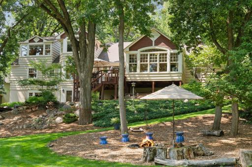 Rear exterior features a spacious three-level deck and cozy firepit with seating, ideal for relaxing under the stars