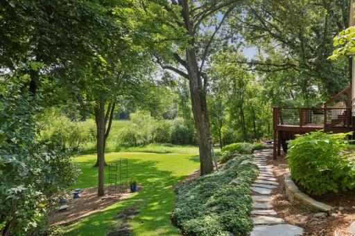 Graceful Flagstaff stone walkway bridges the deck and vibrant landscaping, opening to a sprawling backyard lawn