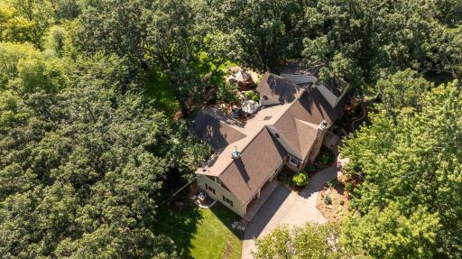 Aerial view captures the home nestled among mature trees, with beautifully landscaped grounds and a serene natural setting