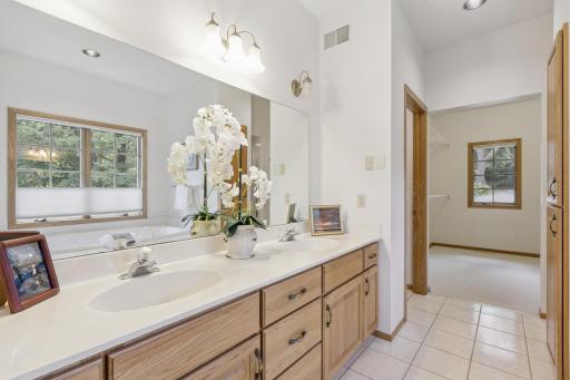 View of the primary bathroom with dual sink vanity, tile floors, jetted tub, walk-in shower, separate stool room and walk-in closet. This expansive ensuite bathroom offers an abundance of space/storage.