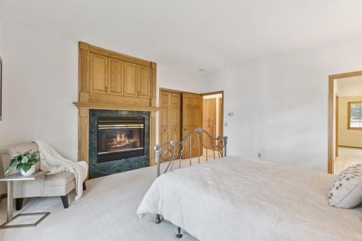 The main floor primary suite features a gas fireplace and an abundance of storage with multiple closets and a large vanity.