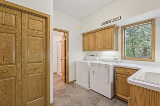 Located in the mudroom between the kitchen and attached garage is the main floor laundry with a wash tub sink, countertop and plenty of storage space.