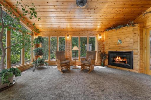 A spacious sunroom with floor-to-ceiling windows framing peaceful views of the surrounding landscape.