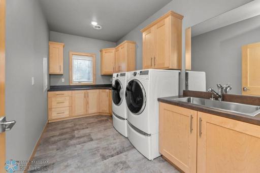 Huge laundry room with utility sink, space to fold, cabinets for storage.
