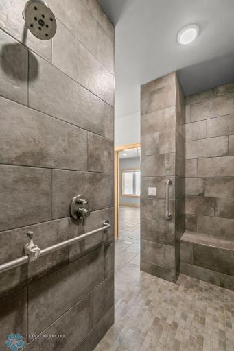 Zero-entry walk-in shower. Fully tiled & curbless with grab bars & bench seat.