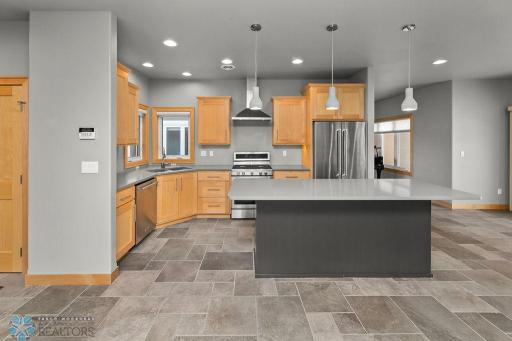 Kitchen features large island, stainless appliances, gas range, island microwave, corner sink, two-tone cabinetry.