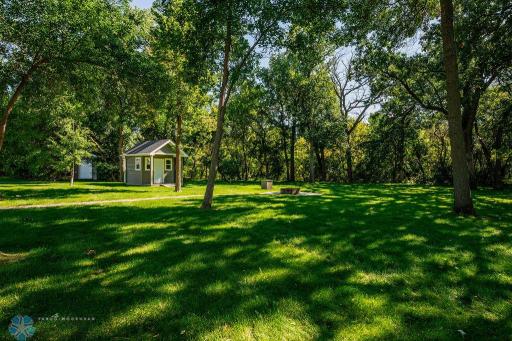 Large, private backyard with trees, storage shed, garage