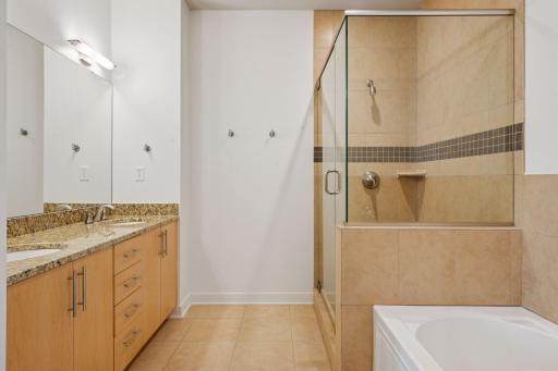 The primary bath blends luxury and function with a spacious double vanity, glass walk-in shower, and deep soaking tub. Designed for both comfort and convenience with thoughtful details, including a linen closet and water closet nook.