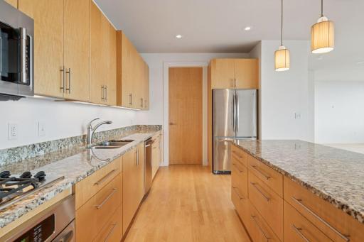 Sleek stainless steel appliances, including a gas cooktop and French-door refrigerator, bring both style and function.