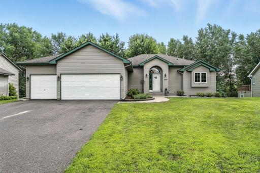 A well-maintained home featuring a welcoming entryway and a three-car garage. The lush green lawn and mature trees provide excellent curb appeal.