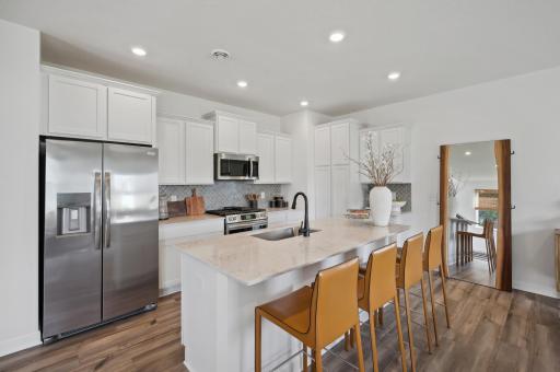 (Photo of decorated model, actual homes color and finishes will vary) A spacious kitchen with an abundance of cabinet space and a large center island providing optimal seating.