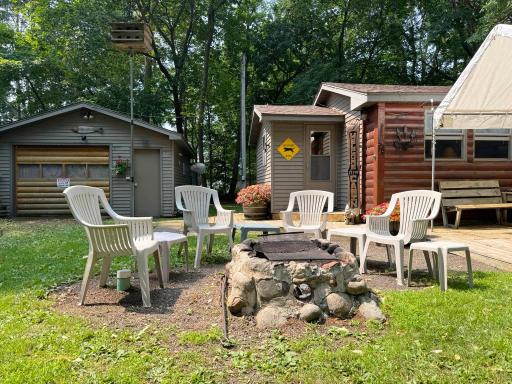 Looking over the firepit with the cabin and garage structure beyond, a great family gathering space!