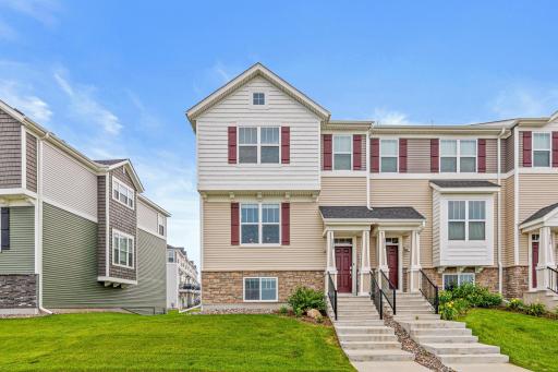 Charming view of the townhome's entrance, showcasing its welcoming front facade and beautifully maintained landscaping.
