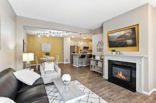 Open Living Room with gas fireplace, abundant natural light, and open flow to the Dining Room and Kitchen.