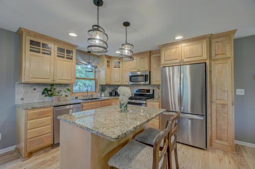 Enjoy effortless cooking in a beautifully updated kitchen featuring a center island with additional seating, granite countertops, maple cabinetry, and stainless steel appliances.