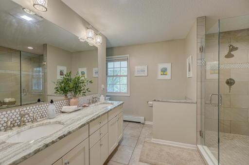Enjoy your private spa-like bath, featuring dual vanities, a beautifully tiled walk-in shower, and ample cabinet space for extra storage