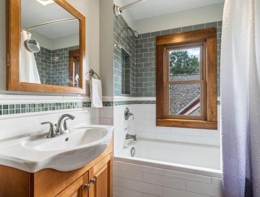 Beautifully tiled shower surround, updated fixtures, and natural light in the full bath