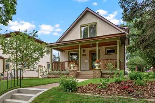 Beautiful curb appeal with lush landscaping, wide front steps, and a welcoming front porch