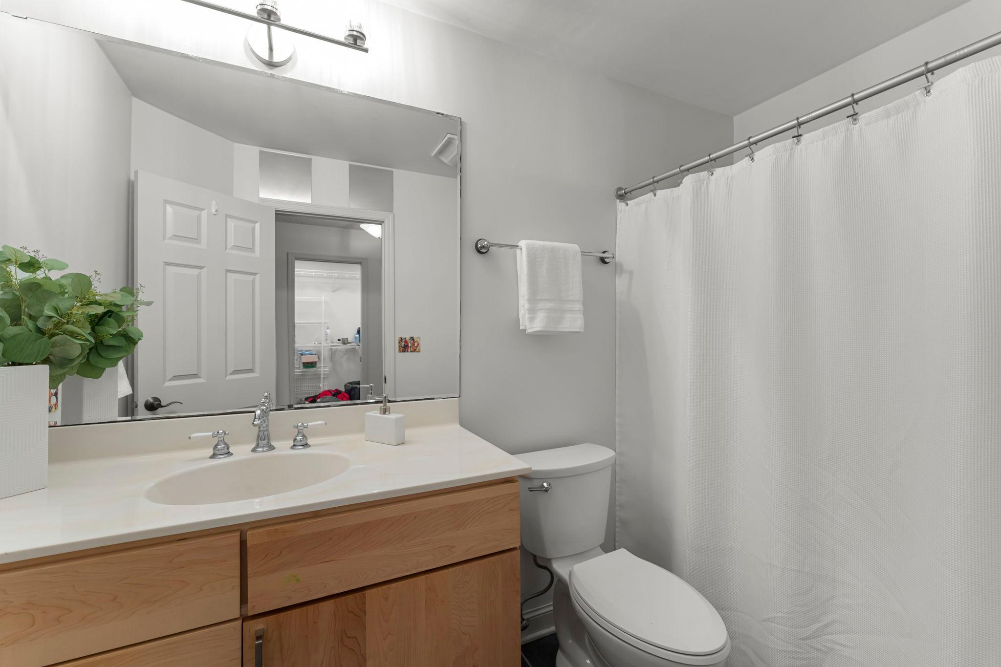 A shared full bathroom is conveniently located, which includes a tub-shower and floor-to-ceiling linen cabinetry for ample storage.