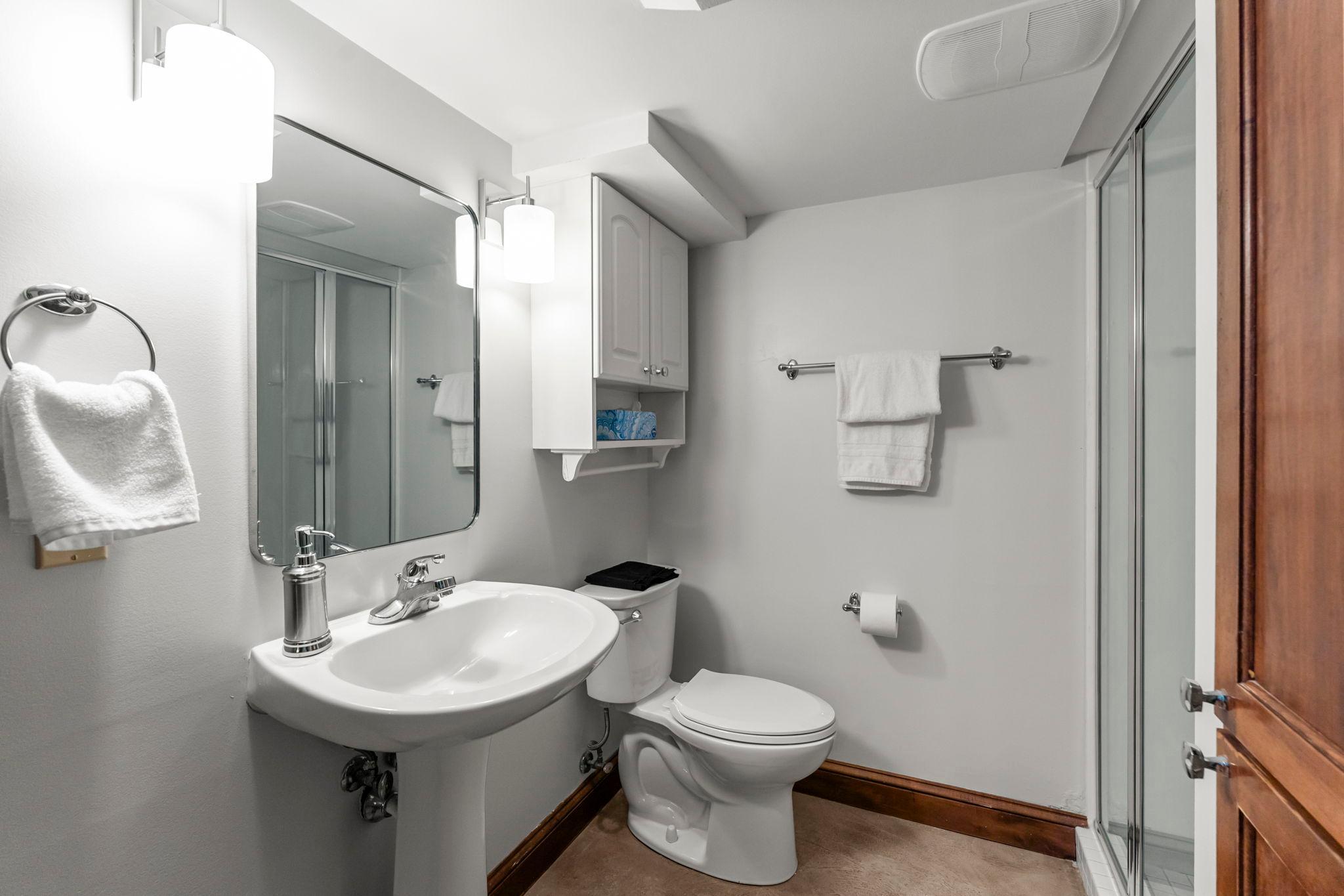A three-quarter bathroom featuring a walk-in tile shower is located nearby. You’ll also find a full-sized refrigerator, a laundry area with a utility sink, and an expansive waterproofed crawl space measuring 13 by 46 feet.