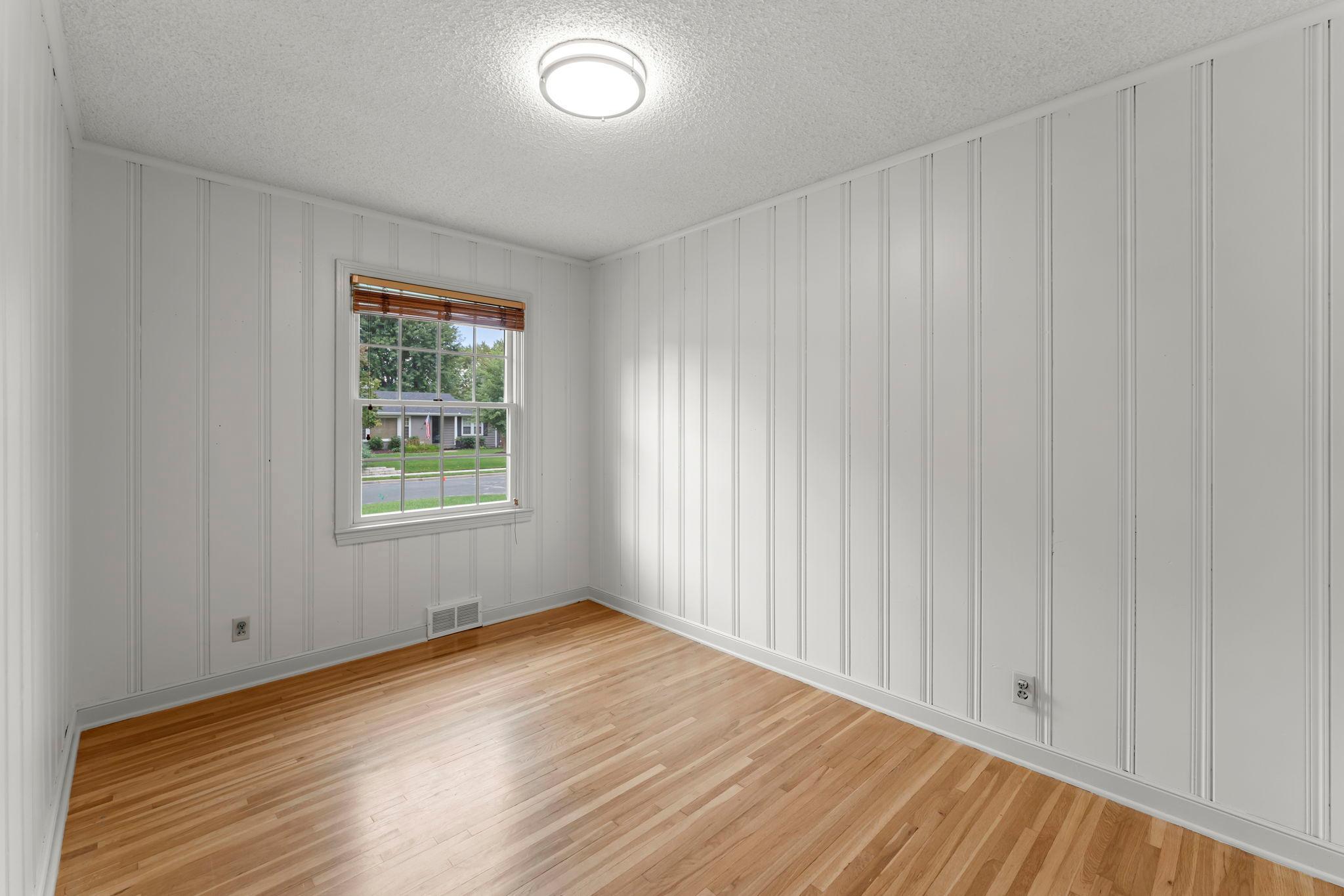 Two additional bedrooms, one accented with wood-paneled walls, are located nearby.