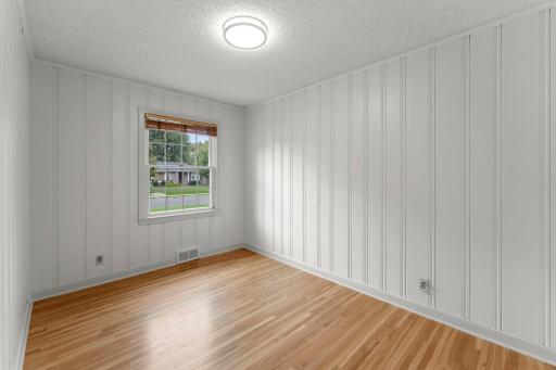 Two additional bedrooms, one accented with wood-paneled walls, are located nearby.
