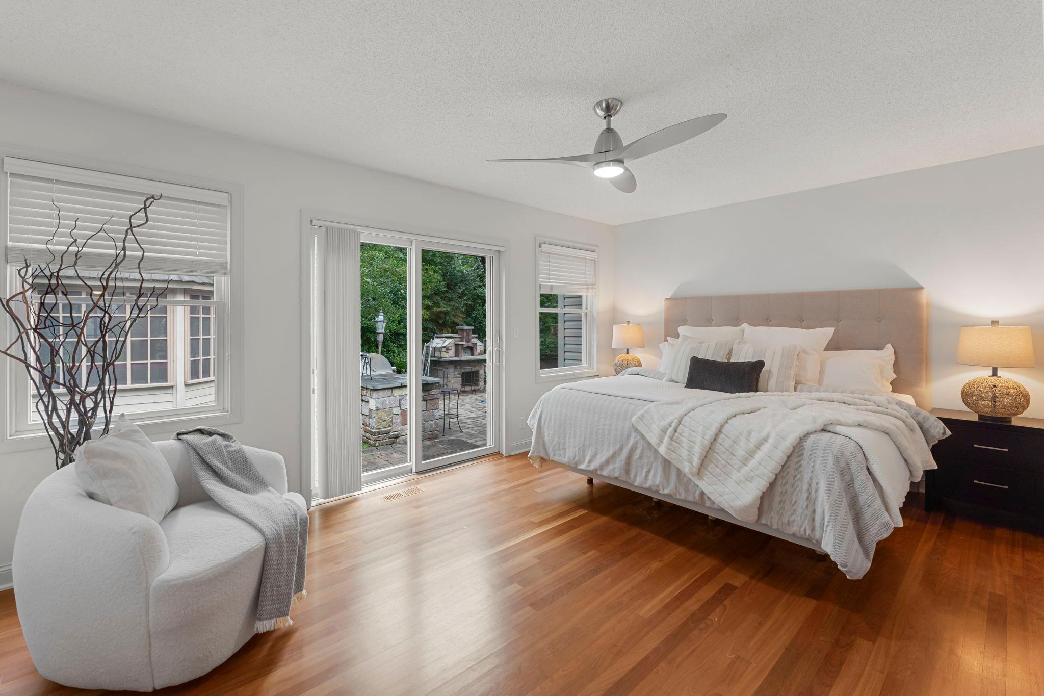 The main level includes three bedrooms, beginning with the expansive primary suite that offers wood flooring, a ceiling fan for year-round comfort, and a walk-in closet with built-in organization.