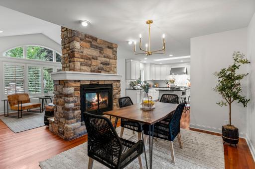 The adjacent dining room features an elegant chandelier and a dramatic two-sided gas fireplace with a stone surround.