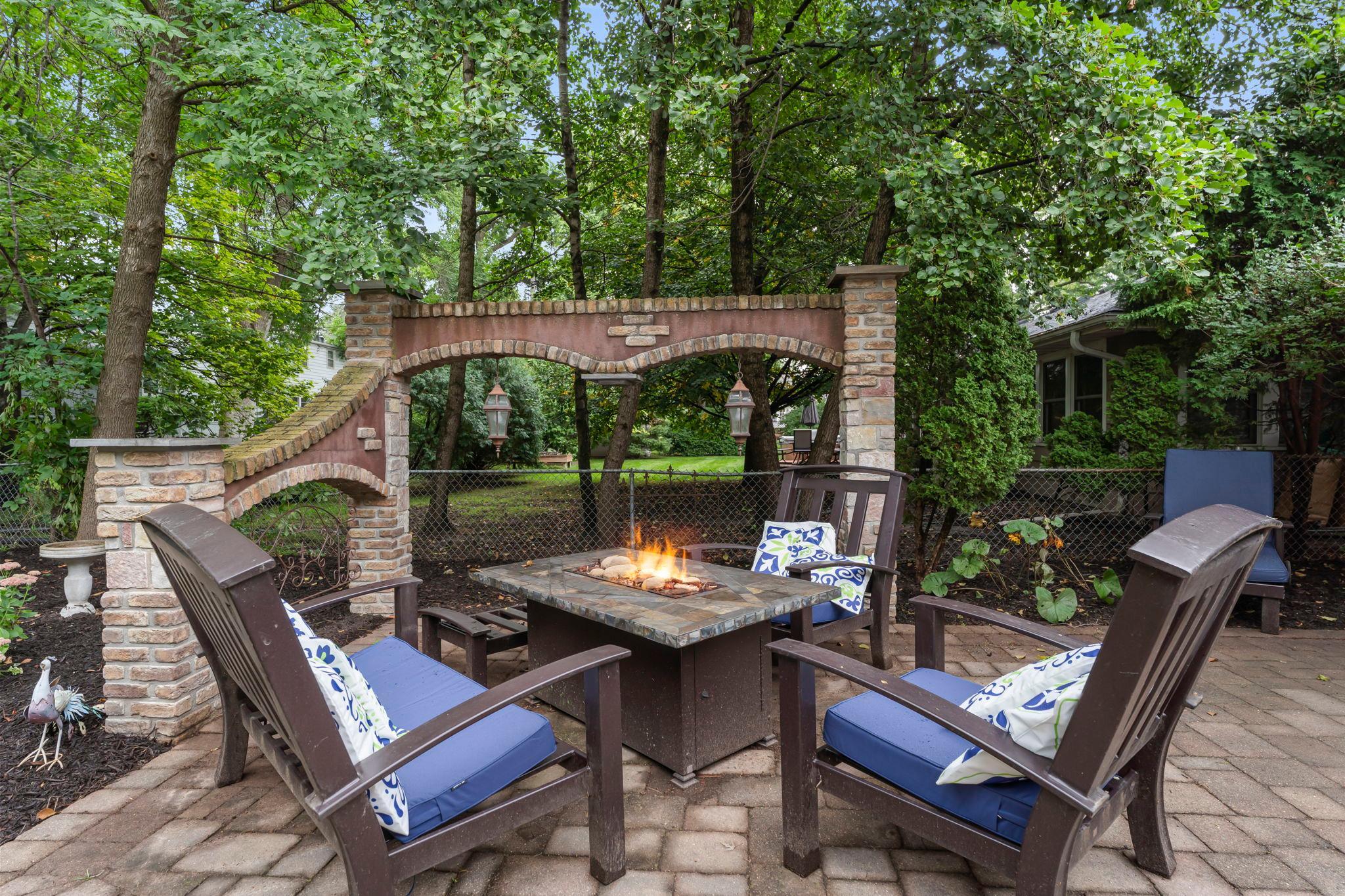 A fire table is set beneath a stunning stone arch. All patio furniture, as well as a beautiful fountain, are included with the home.