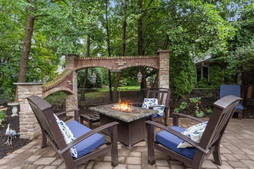 A fire table is set beneath a stunning stone arch. All patio furniture, as well as a beautiful fountain, are included with the home.