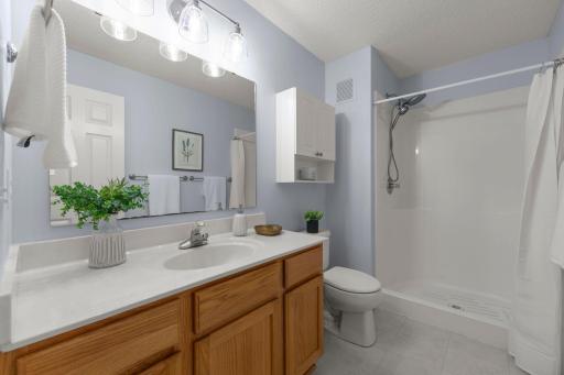 The private primary bathroom has a long vanity and step in shower.