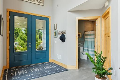 Welcoming front entrance features a stylish double-door entry, tiled floors, convenient bath, and a spacious coat closetâcomplete with a hidden safe for added peace of mind.