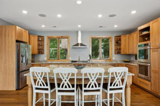 Chefâs kitchen with stainless vent hood and peaceful wooded views offering backyard privacy.