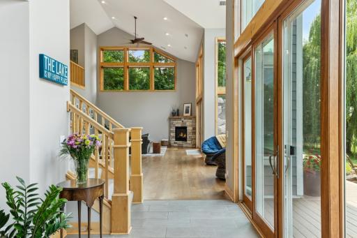 Looking out from the front door, you're greeted with soaring ceilings, a wall of windows, and a cozy fireplaceâoffering a stunning first impression and seamless flow to the deck and backyard beyond.
