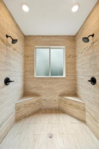 Spacious walk-in shower with floor-to-ceiling tile and dual shower headsâdesigned for both luxury and function.