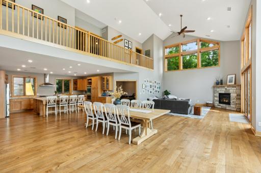 Impressive great room featuring 23-ft ceilings, white oak floors, and an open layout seamlessly connecting the kitchen, dining, and living areas.