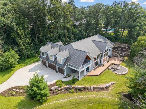 Expansive concrete driveway leads to a spacious, heated, 4-car garageâperfect for storing lake toys, vehicles, or extra gearâall framed by manicured landscaping and striking curb appeal.