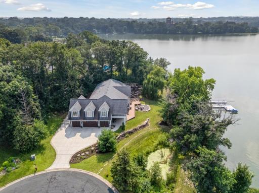 Aerial view captures this stunning home tucked at the end of a quiet cul-de-sac, offering privacy, expansive lake frontage, and direct access to the association beach just steps away.