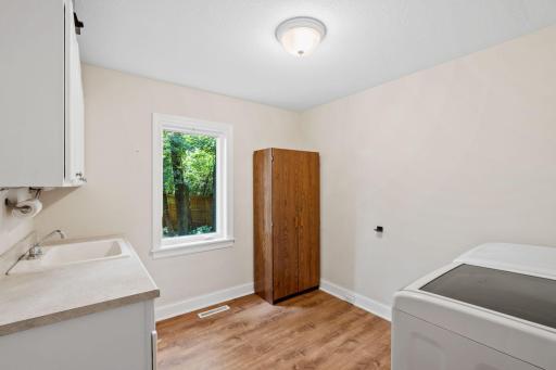 Spacious main level laundry room with sink, storage and a pantry cabinet. Cabinet will be staying with the home.