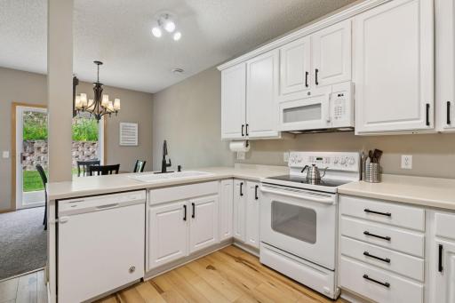 White cabinetry and appliances with wood laminate flooring to compliment.