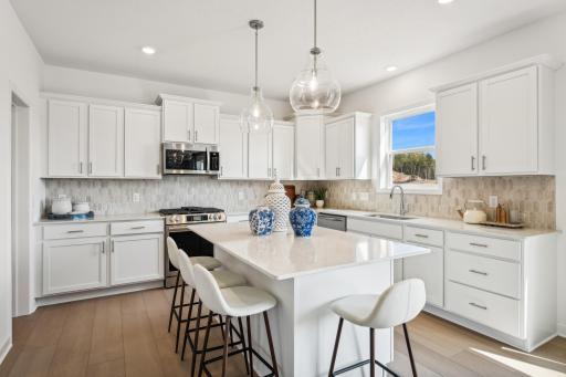 (Photo of a decorated model, actual homes finishes will vary) Welcome to the Lewis! This spacious kitchen features a large center island, quartz countertops, LVP floors, stainless appliances and more.