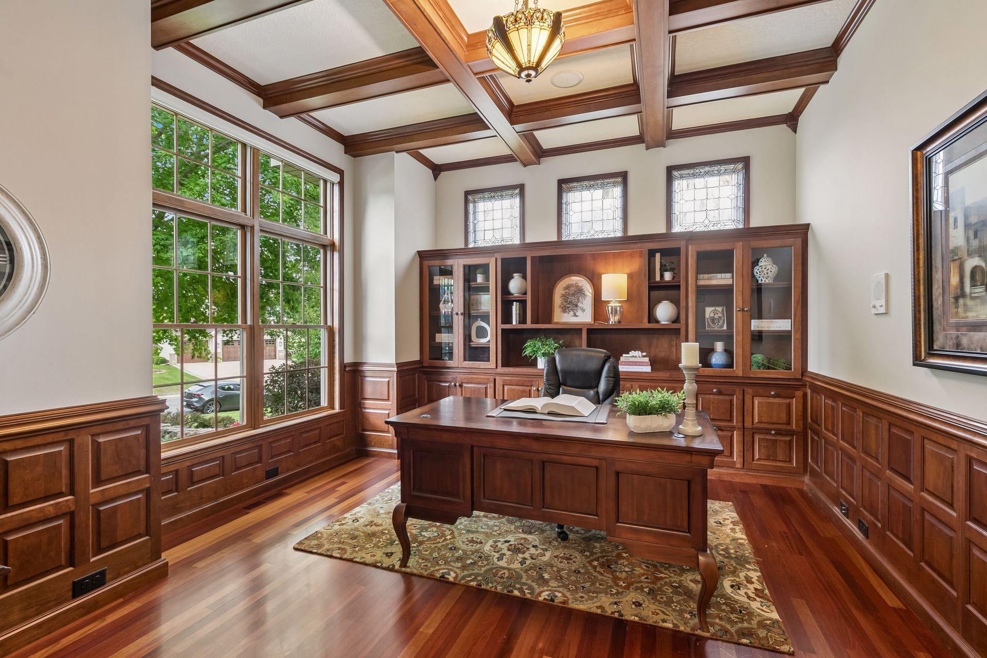 Large main level office with coffered ceiling and cherry wood built-ins and paneling